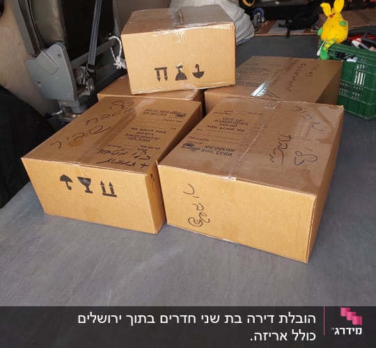 ארבעה קרטונים חומים עם כיתוב בעברית ברכב הובלה